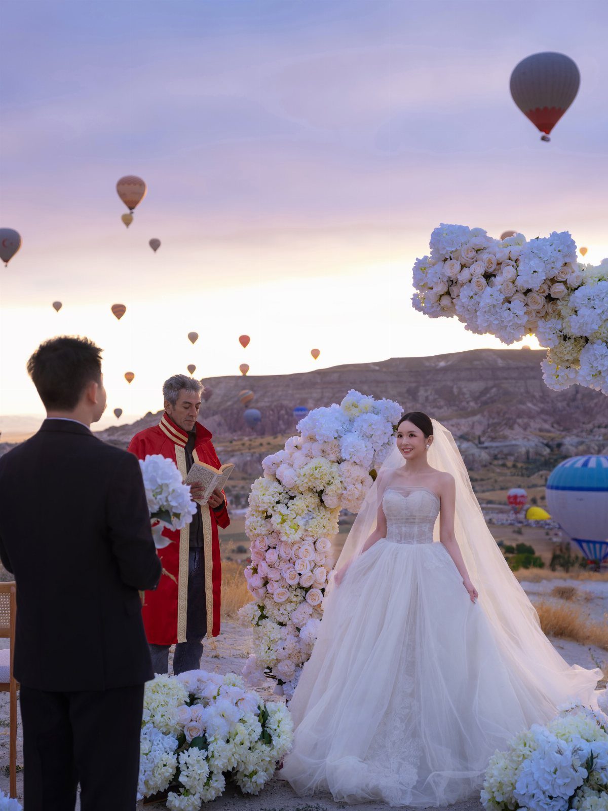 Bride and groom during a wedding ceremony with hot air balloons in the sky