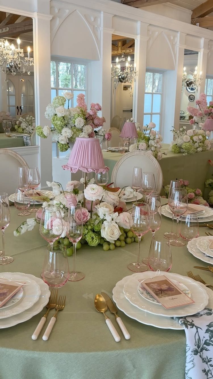 Ornate white and pink floral centerpieces on a sage green wedding table setting.