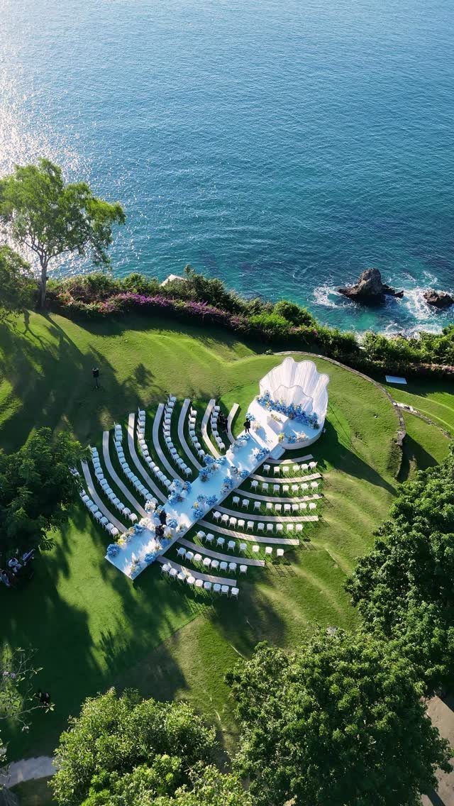 Outdoor wedding ceremony setup with white chairs on a cliff overlooking the ocean.