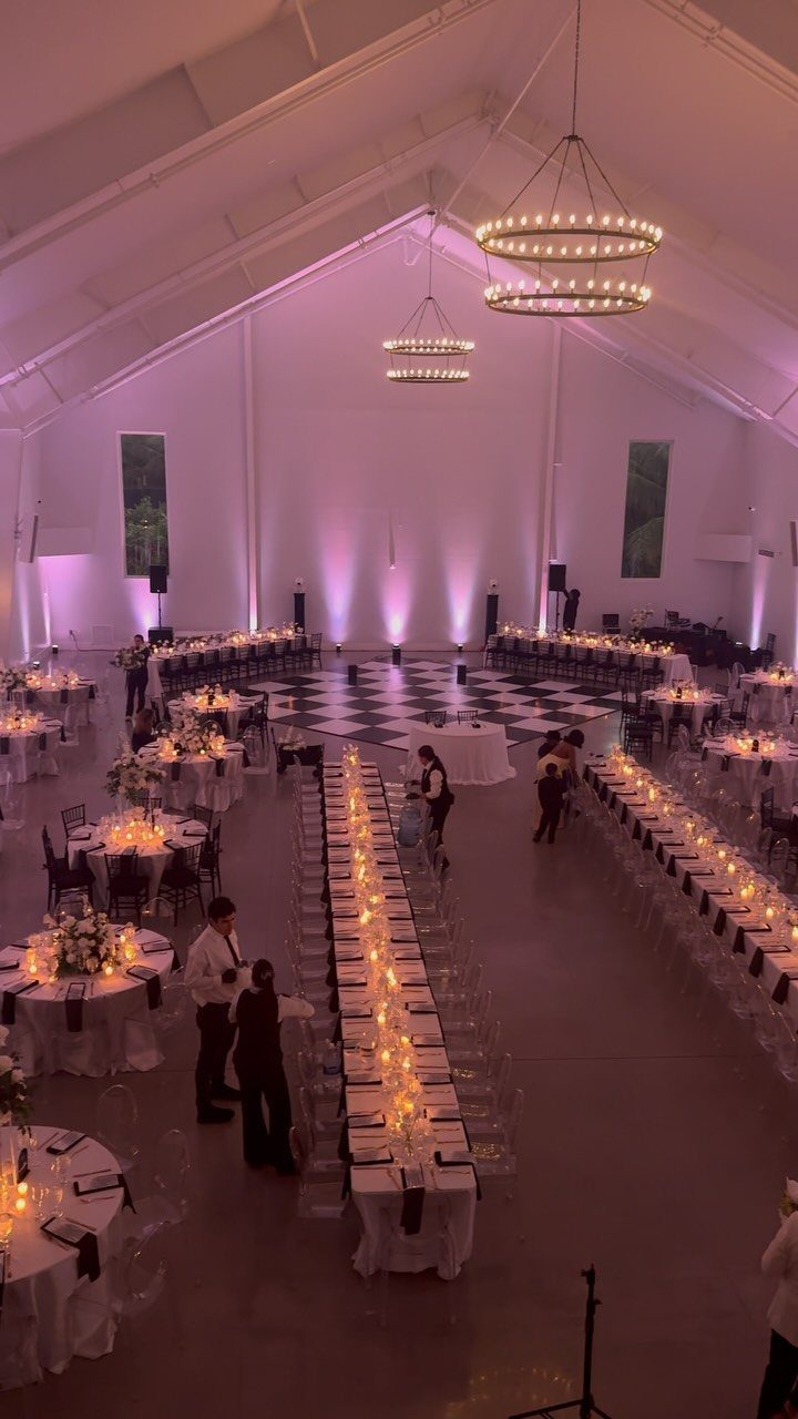 Wedding reception hall with long banquet tables, round tables, and checkered dance floor.