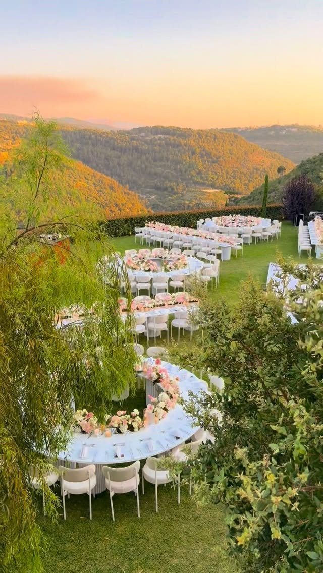 Outdoor wedding reception with white tables and floral centerpieces overlooking a mountain valley.