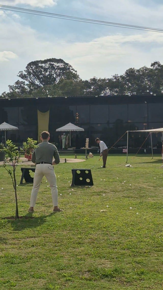 Two men playing a lawn game with target boards on a grassy field.