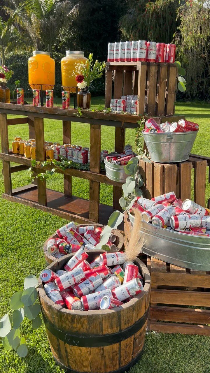 Wooden drink station with orange juice dispensers and red cans in barrels and tubs.