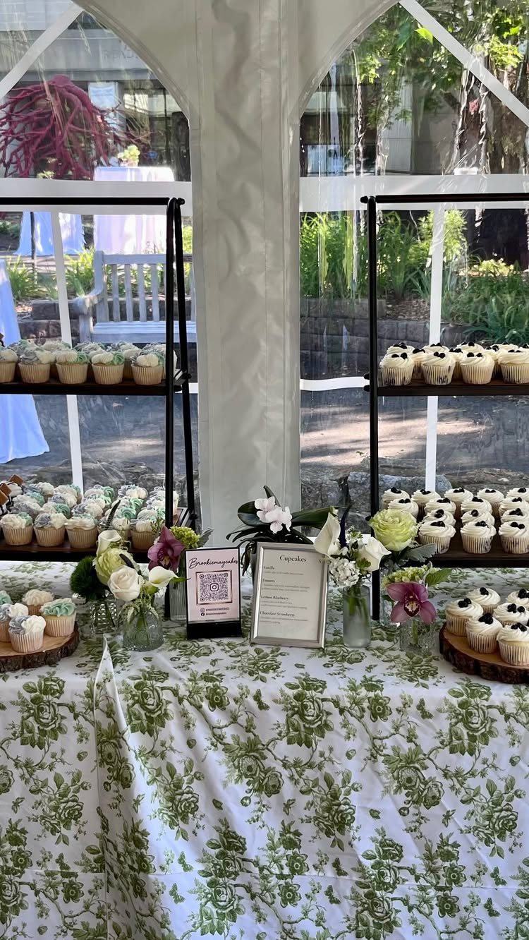 Dessert table with cupcakes and flowers under a white wedding tent.