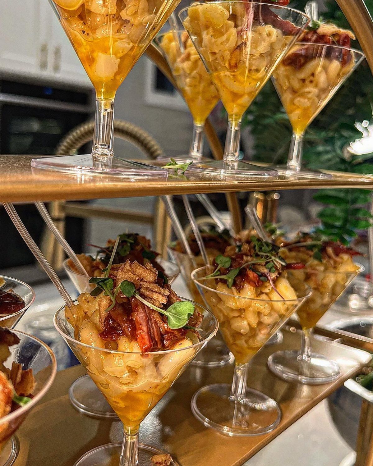 Macaroni and cheese with bacon toppings served in elegant martini glasses on a stand.