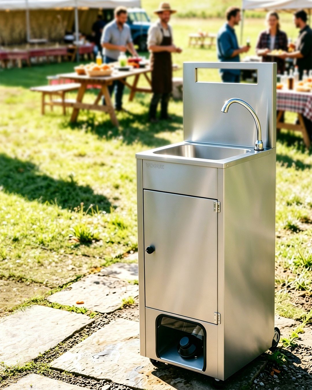Portable stainless steel outdoor sink on a stone path at a backyard gathering.