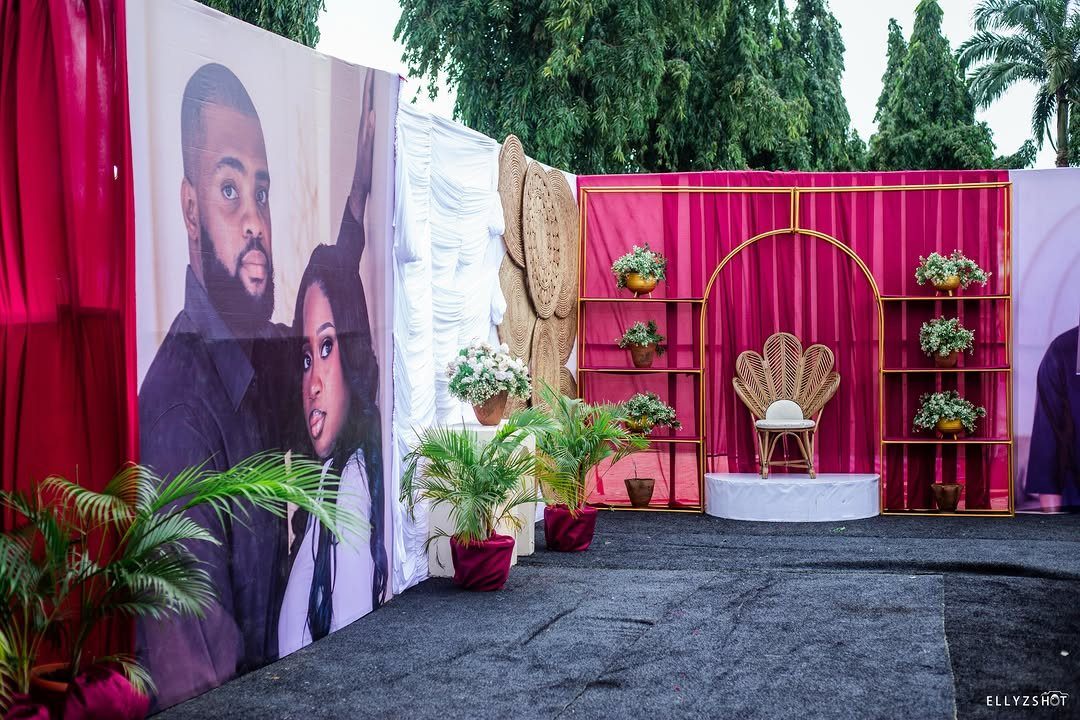 Gold peacock chair centered in a pink and gold wedding backdrop setup.