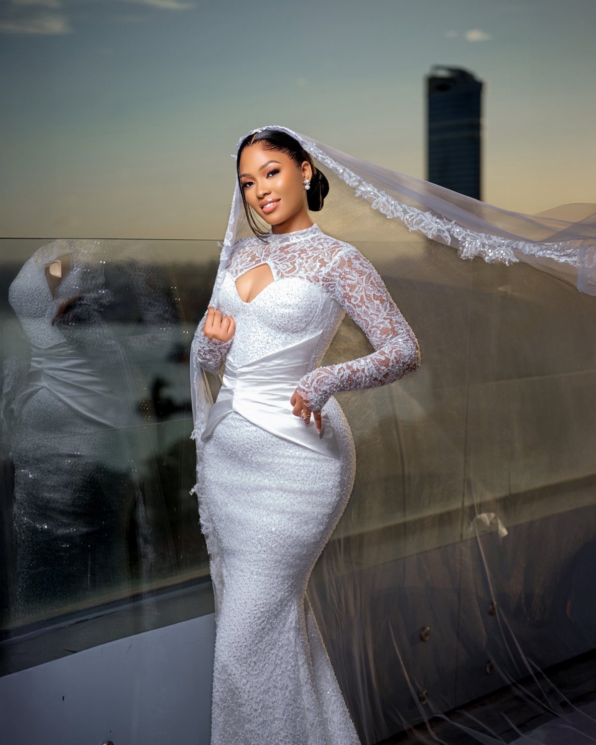 Black bride in a white lace wedding gown and veil posing on a balcony