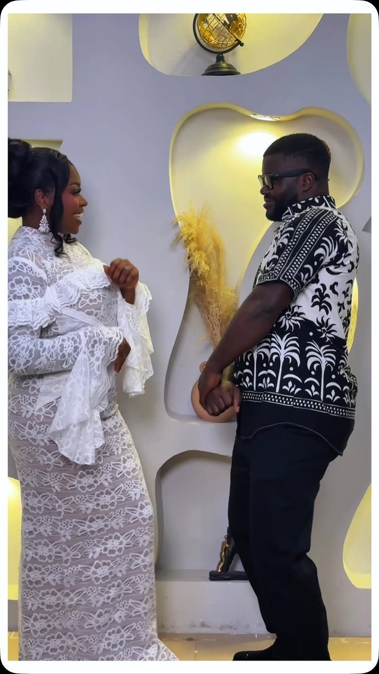 Black couple in wedding attire facing each other in a modern interior setting