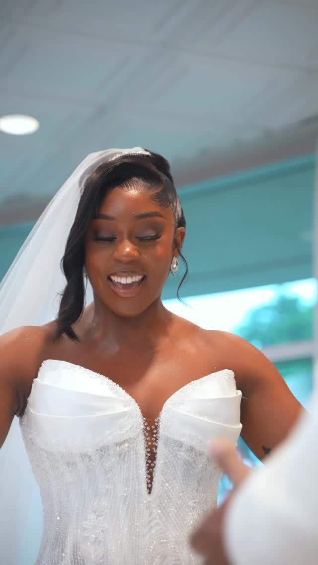 Smiling Black bride in a white beaded wedding gown and veil.