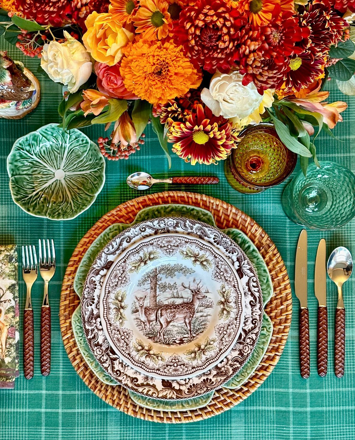 Table setting with teal checkered cloth, autumn flowers, and decorative deer plate.