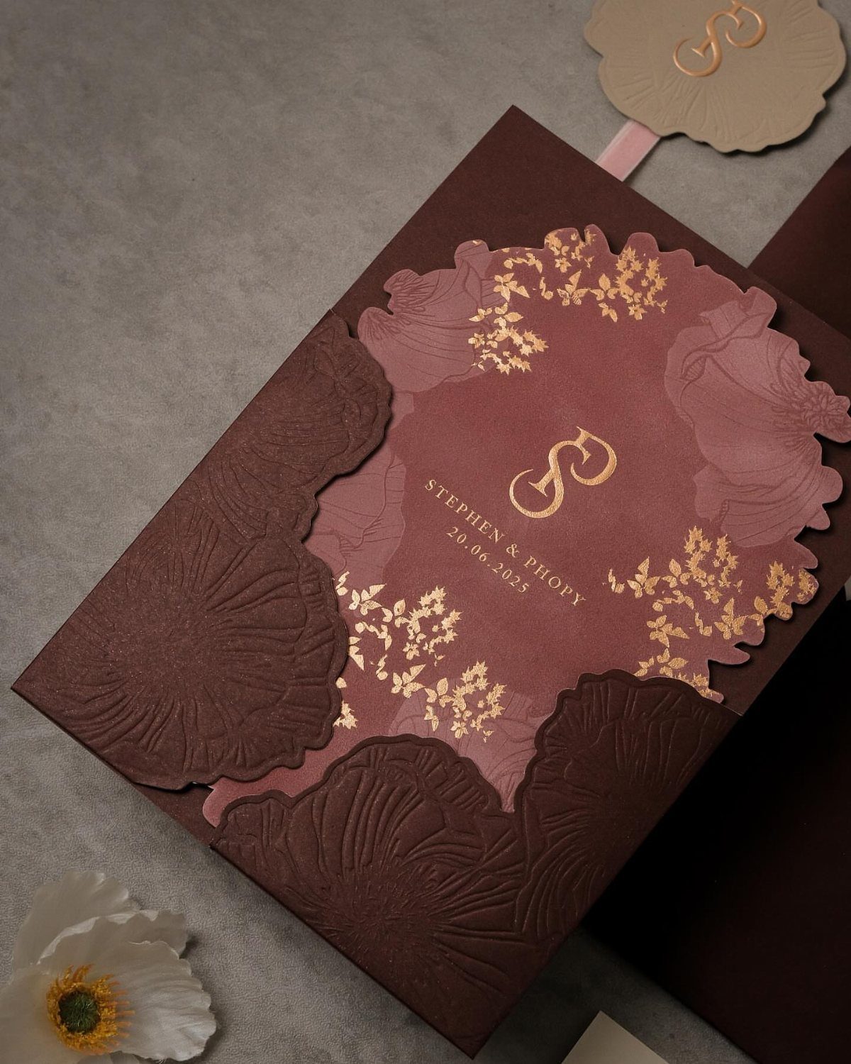 Burgundy and mauve wedding invitation with gold foil lettering and embossed floral textures.