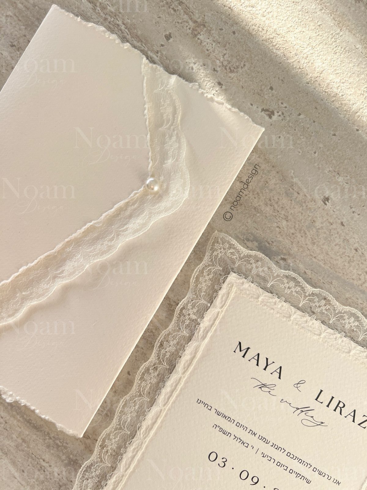 Wedding invitation card with lace trim and a pearl-sealed white envelope.