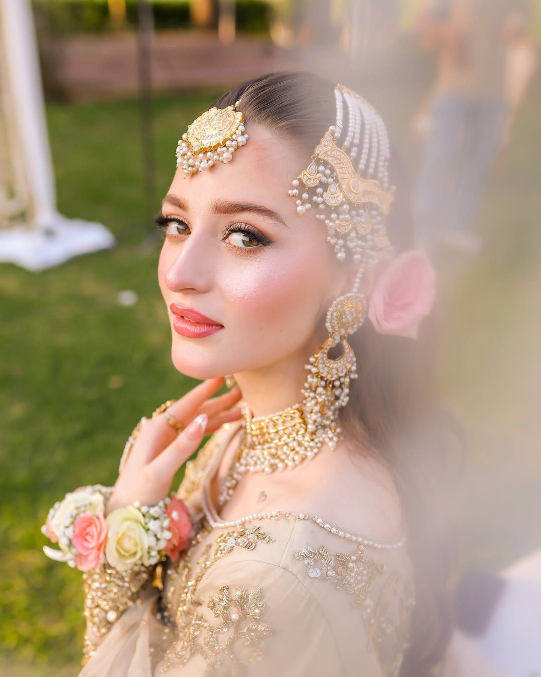 Woman wearing a gold and pearl bridal maang tikka and traditional jewelry