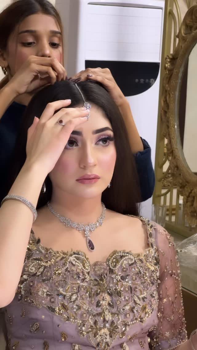 Woman wearing a silver maang tikka and purple bridal dress being styled