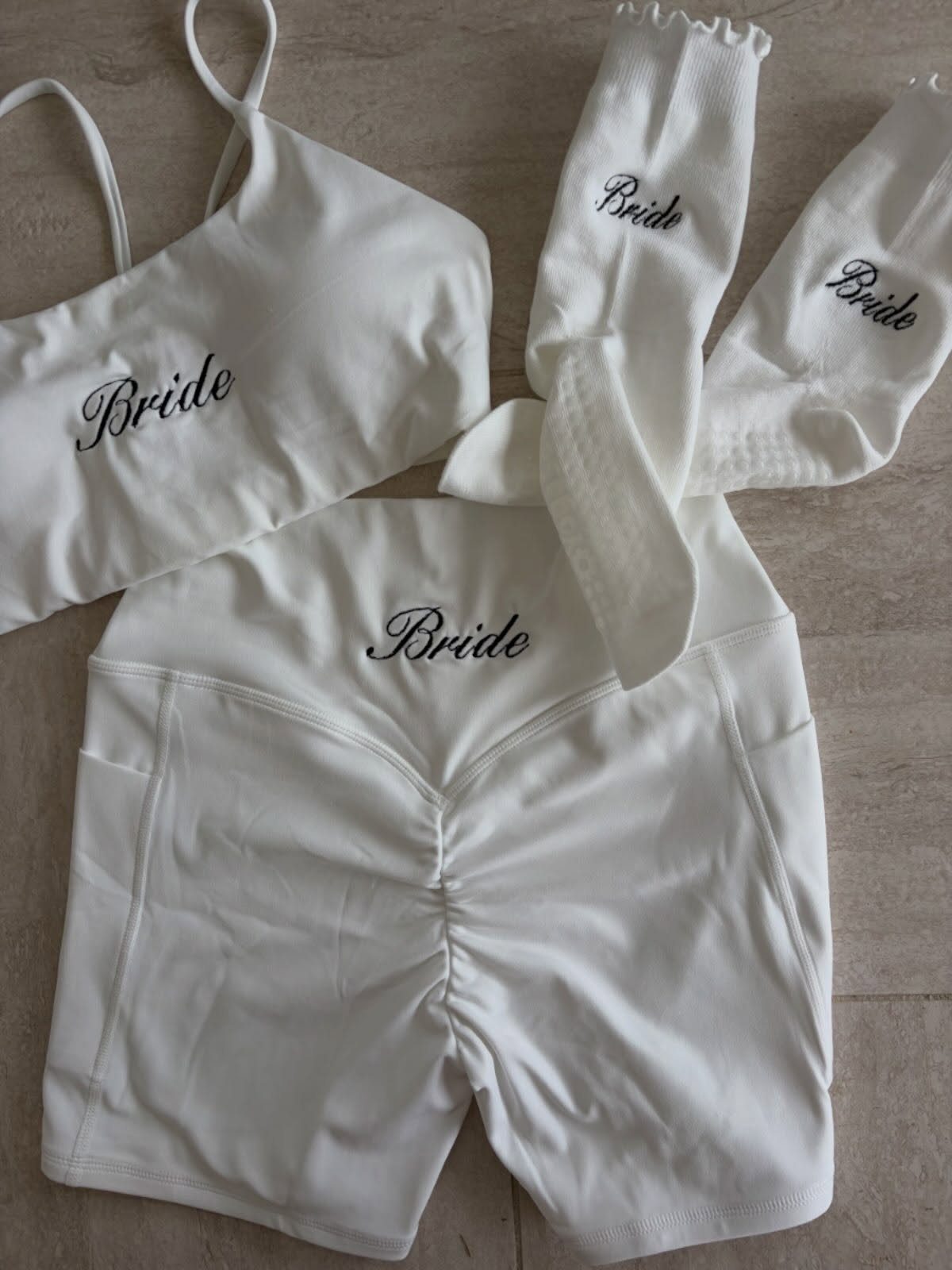 White bridal activewear set with sports bra, biker shorts, and socks embroidered with Bride