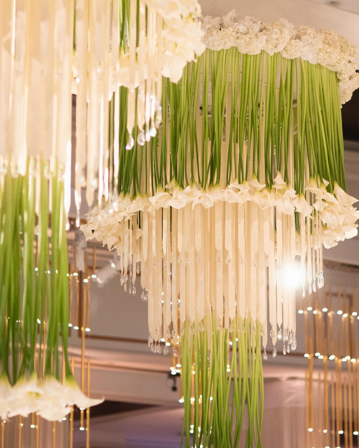 Suspended white calla lilies hanging upside down in tiered cylindrical installations from a ceiling.