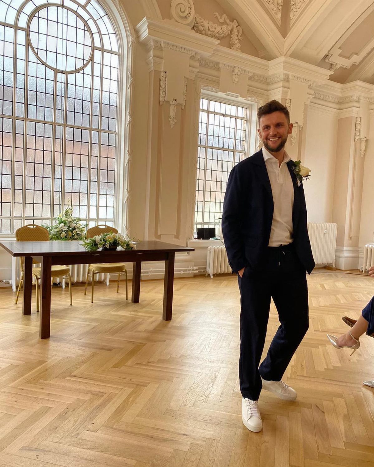 Man in navy blazer and trousers with white sneakers in a bright room