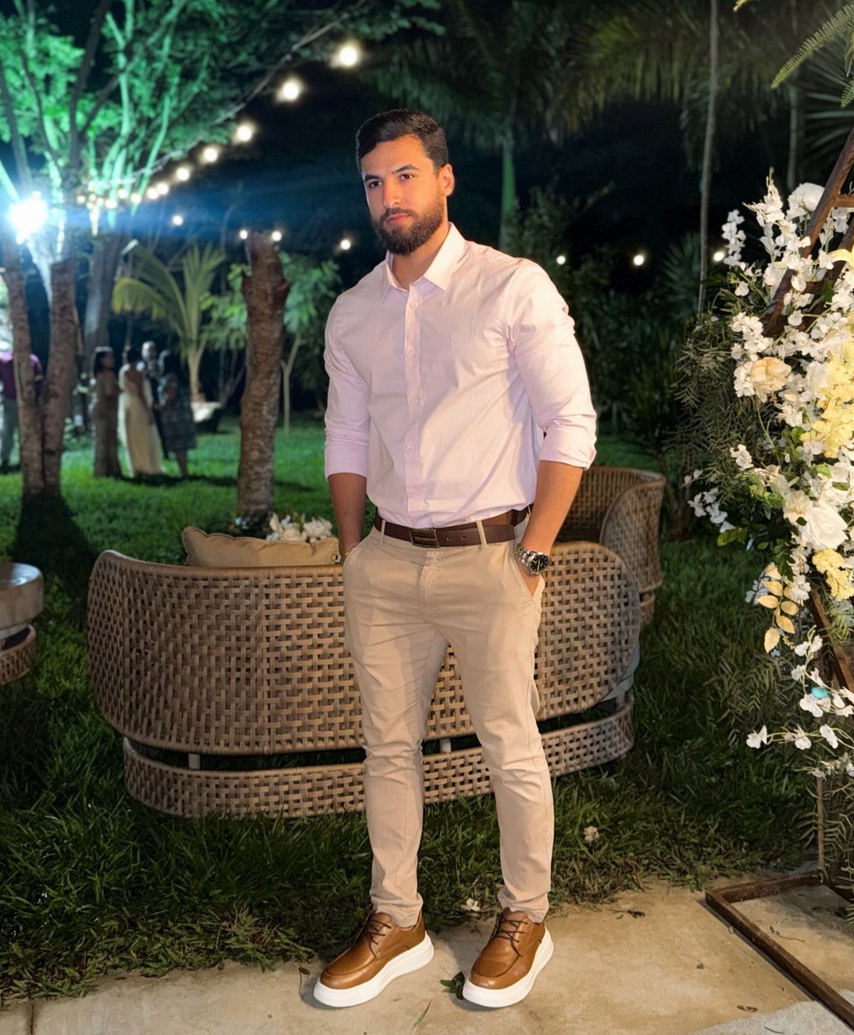 Man wearing a white button-up shirt and khaki pants at an outdoor event.