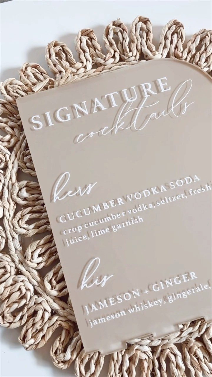 Acrylic signature cocktail sign resting on a woven straw placemat