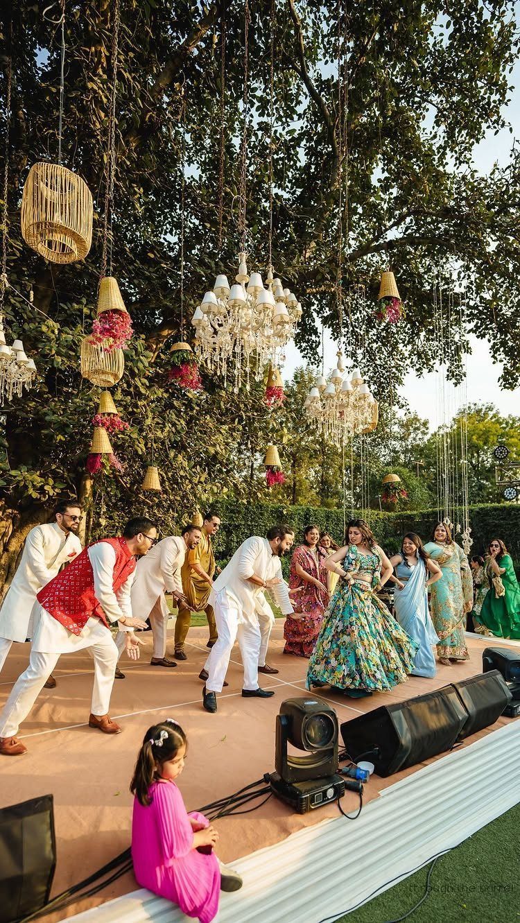Group of people in traditional Indian wedding attire dancing on an outdoor stage