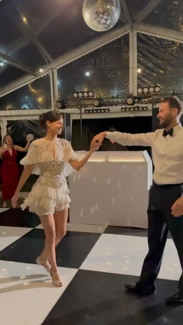 Couple dancing on a checkered floor in formal attire under a disco ball