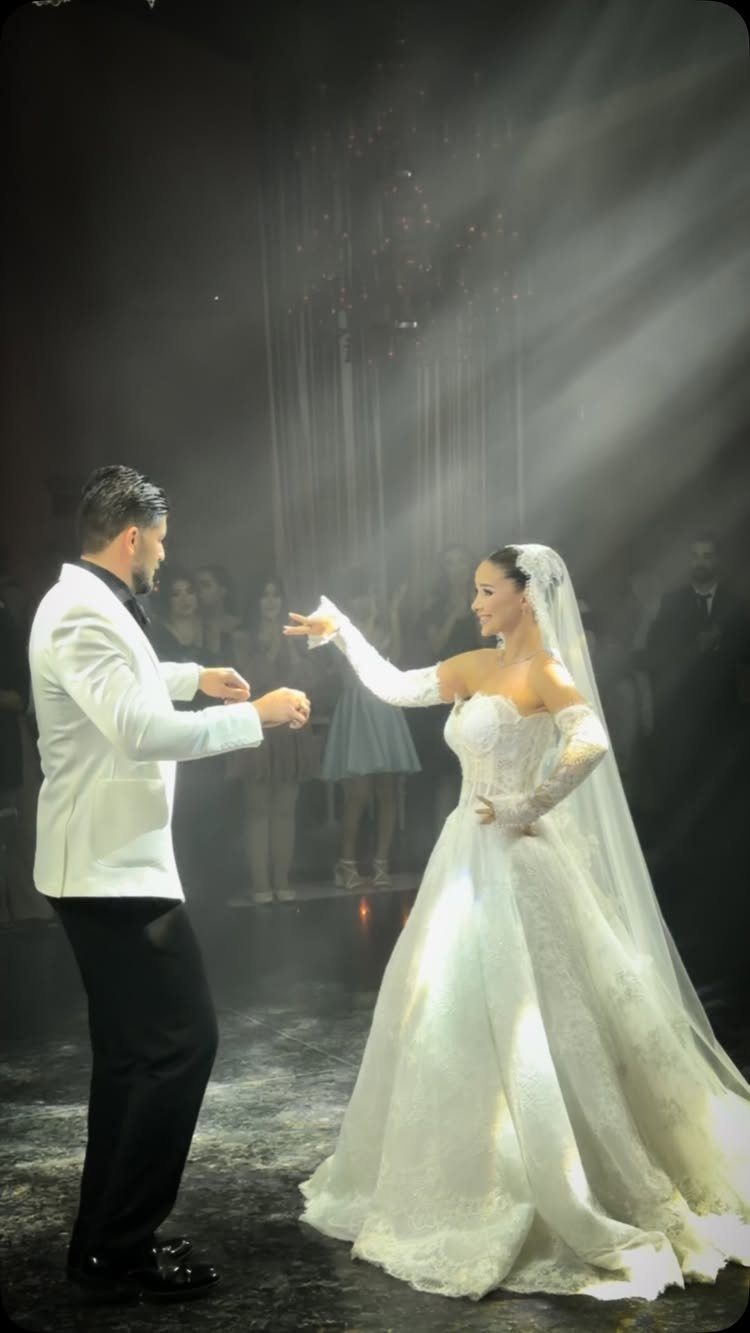 Bride and groom dancing their first dance under dramatic spotlights at a wedding.