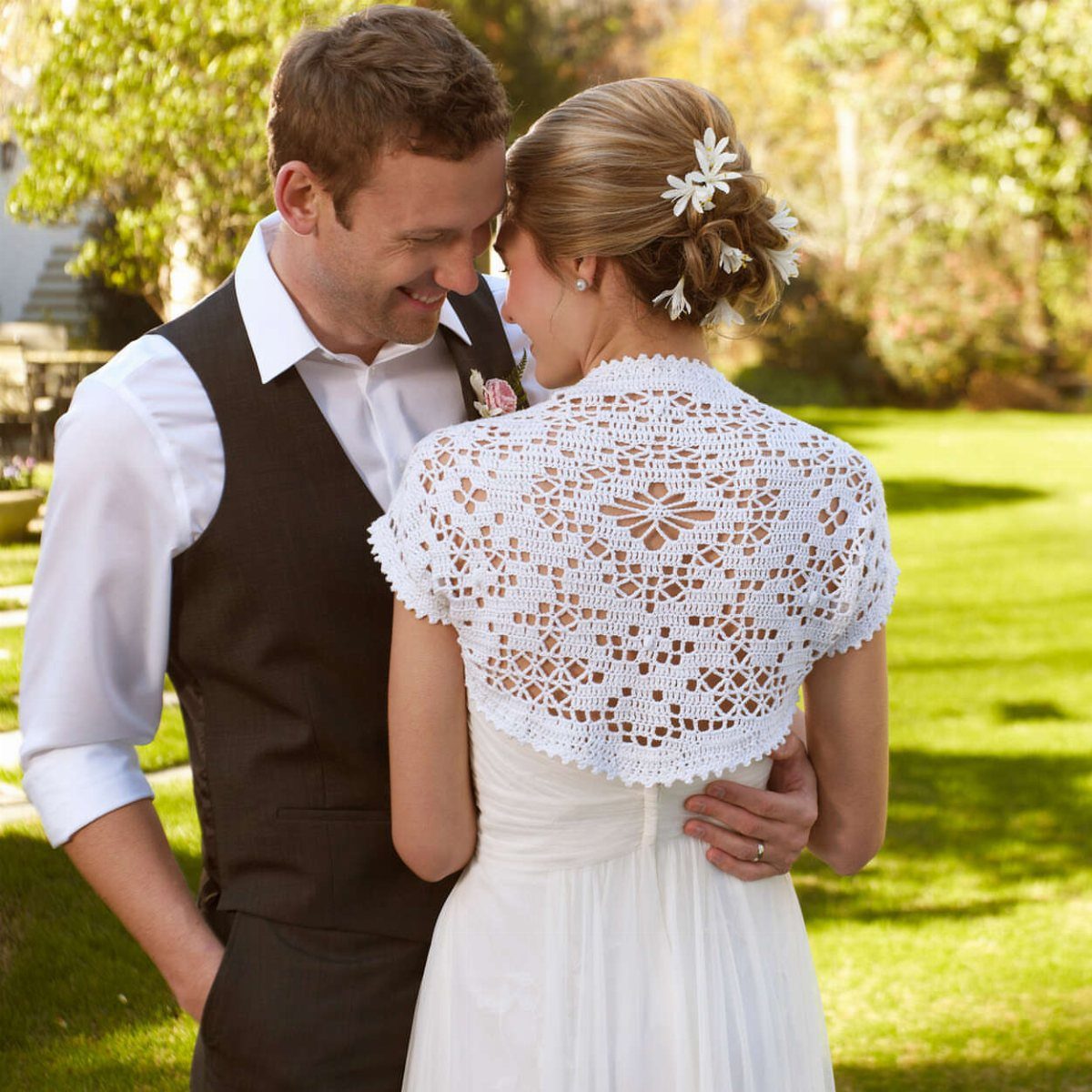 Bride wearing a white crochet shawl over her wedding dress in a garden