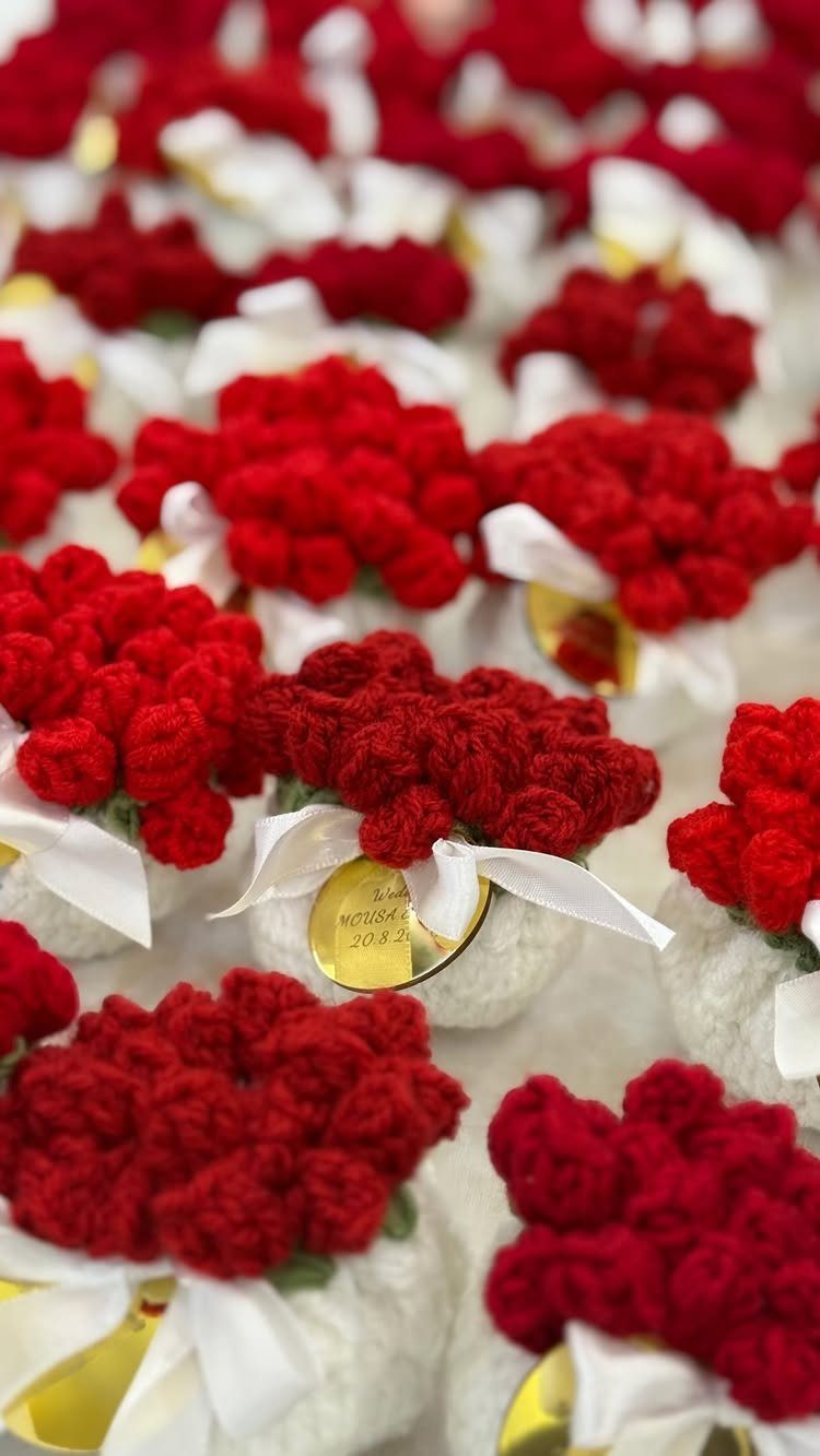 Small crochet red flower bouquets with white ribbons and gold tags for weddings.