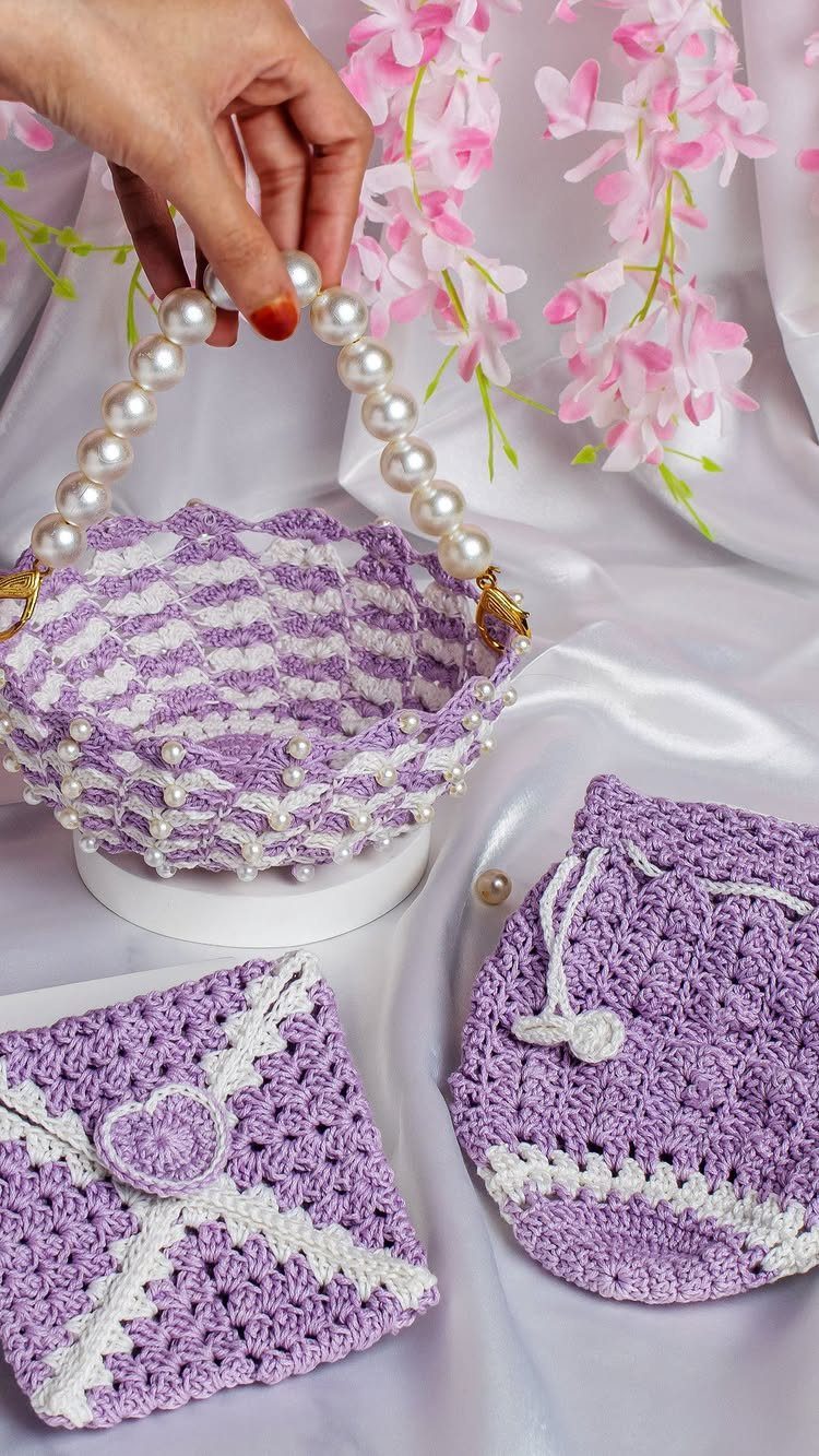 Purple and white crochet basket, pouch, and square on white satin fabric.