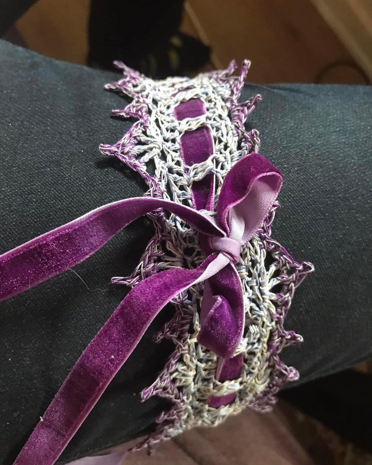 Purple and white crochet lace garter with a velvet bow on a leg