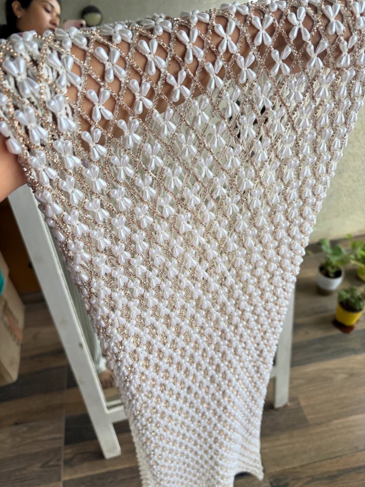 White lacy crochet bridal shawl with floral patterns and small white pearls.