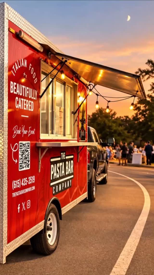 Red pasta food truck with string lights parked at an outdoor evening event.