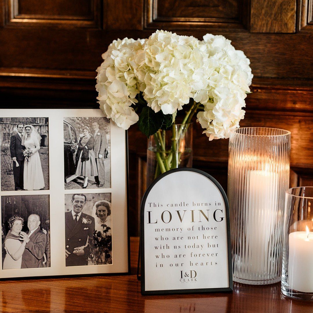 Memory table with vintage wedding photos, white hydrangeas, and a memorial candle sign.