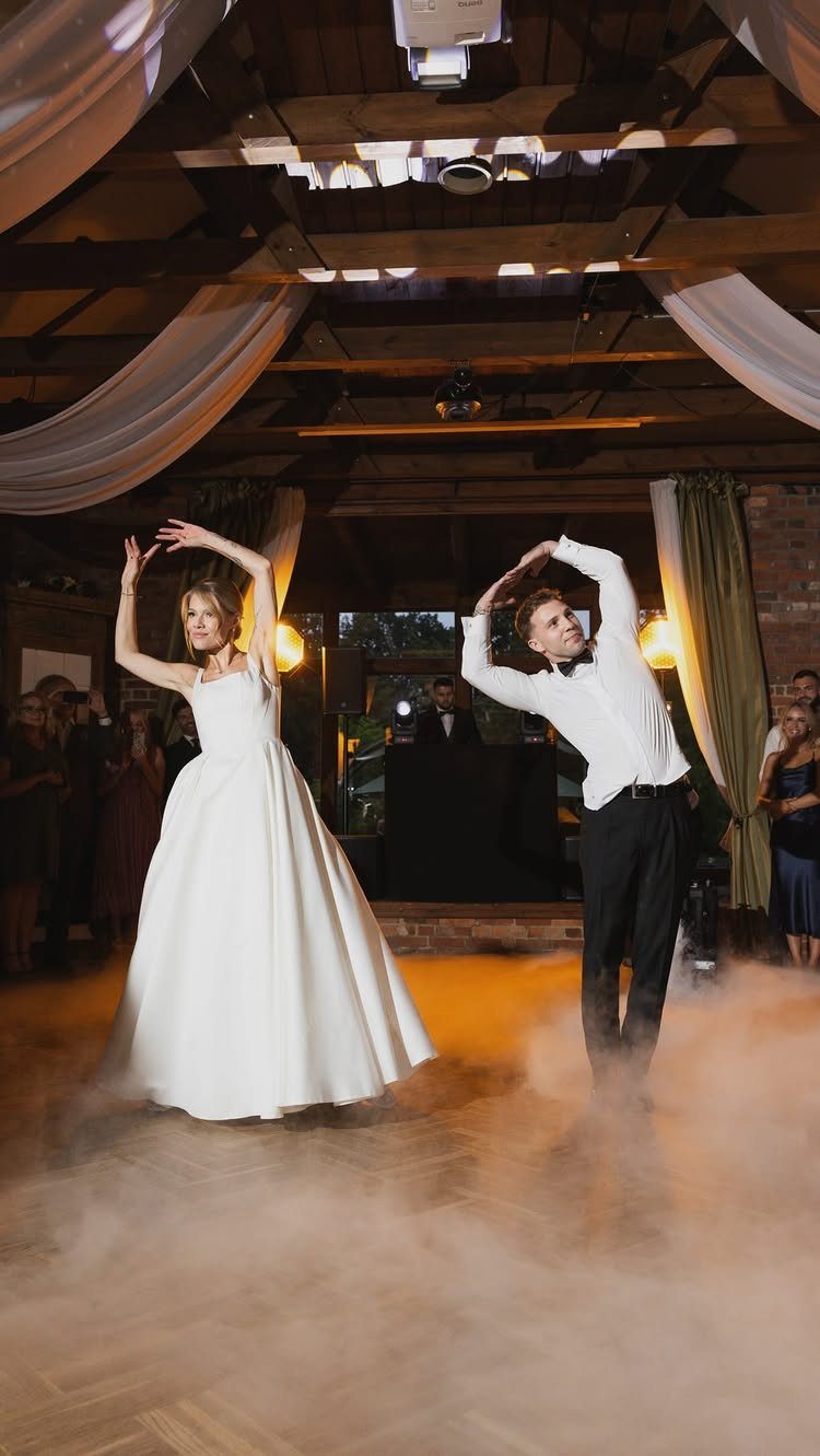 Bride and groom dancing in a rustic venue with low-lying fog on floor