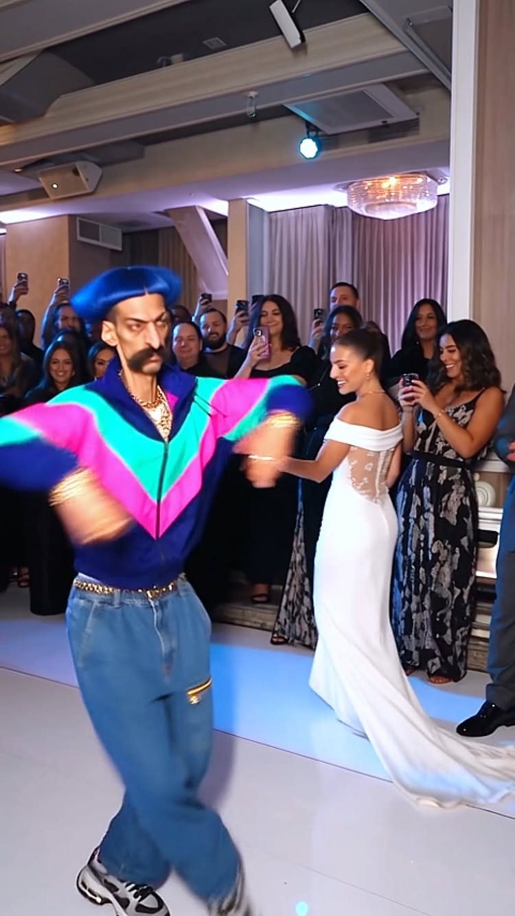 Bride in white gown dancing with man in colorful neon tracksuit at wedding party