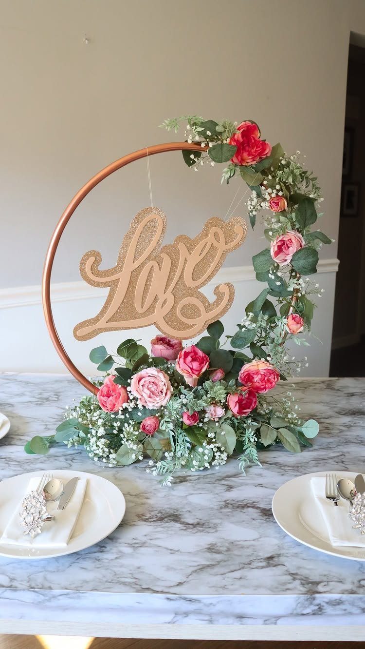 Copper hoop backdrop decorated with pink roses and a gold Love sign.