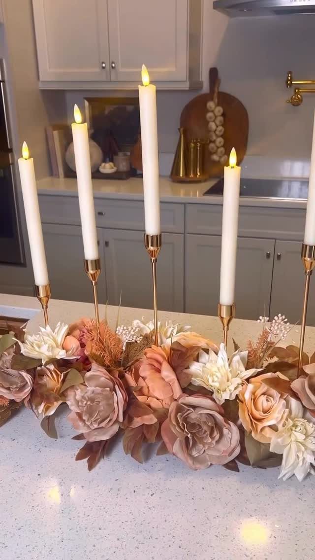Floral centerpiece with peach and cream roses and tall white taper candles.