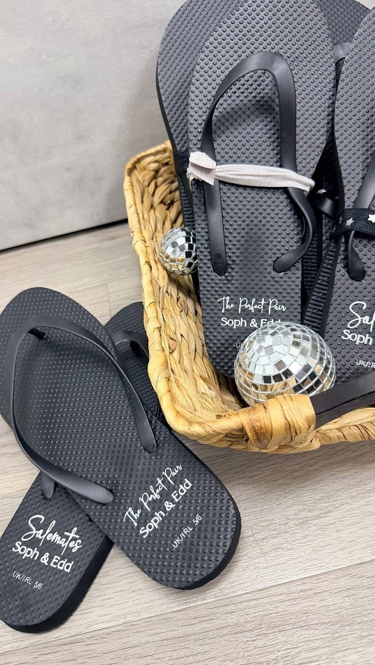 Black personalized flip-flops for wedding guests in a wicker basket with disco balls.