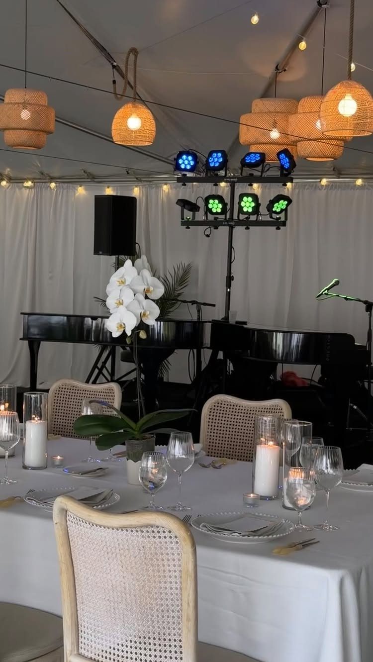Two black grand pianos set up for a wedding reception with elegant table settings.