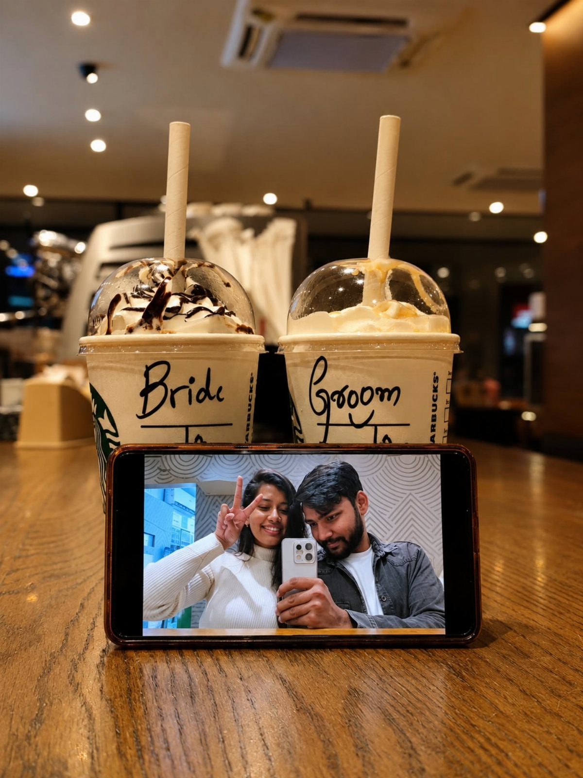Two Starbucks drinks labeled Bride and Groom next to a phone showing a couple