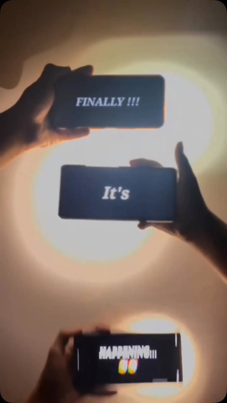 Three smartphones held by hands displaying the words Finally It's Happening with hearts.