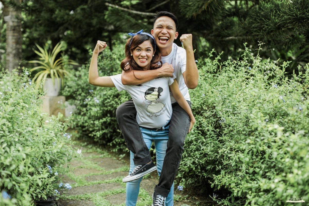 Man giving a woman a piggyback ride while smiling in a green garden