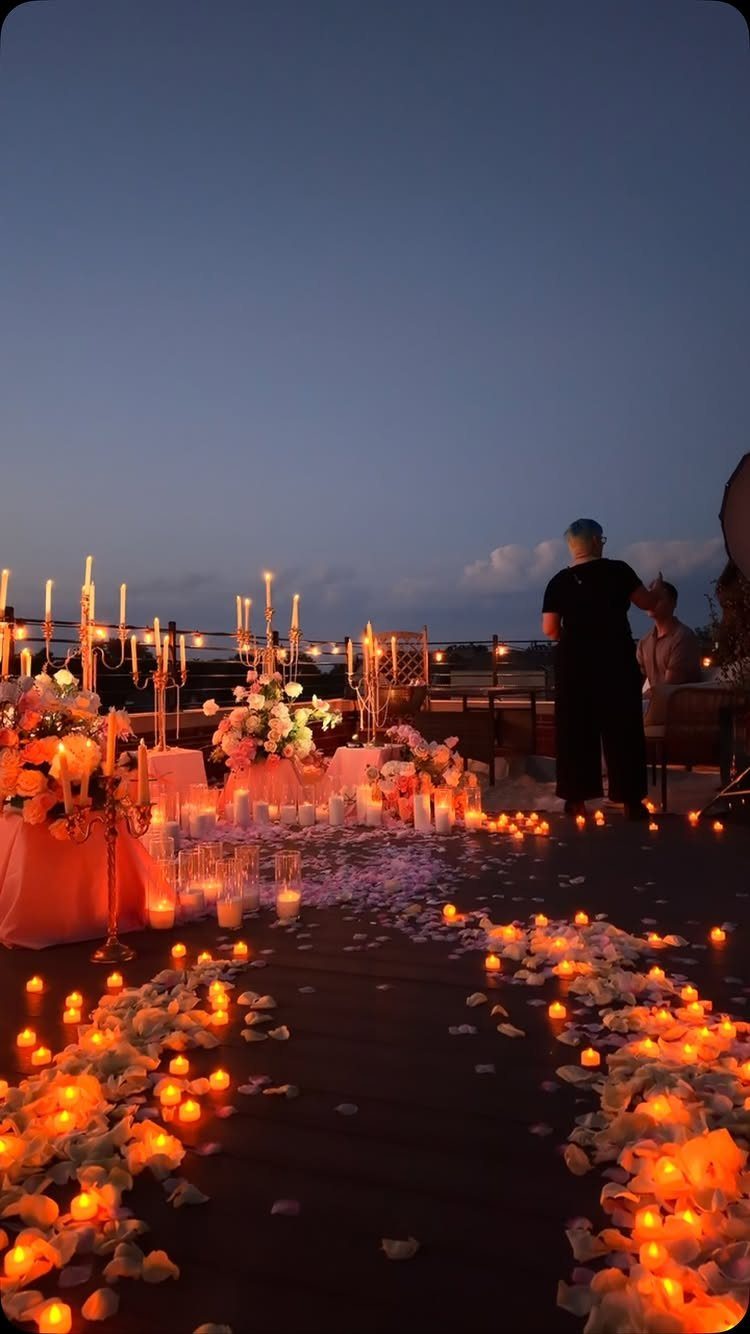 Rooftop proposal setup with candlelit petal path and romantic floral table decorations.