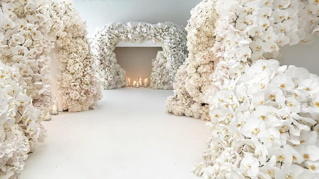 White orchid floral arches and walls creating a whimsical wedding ceremony space.