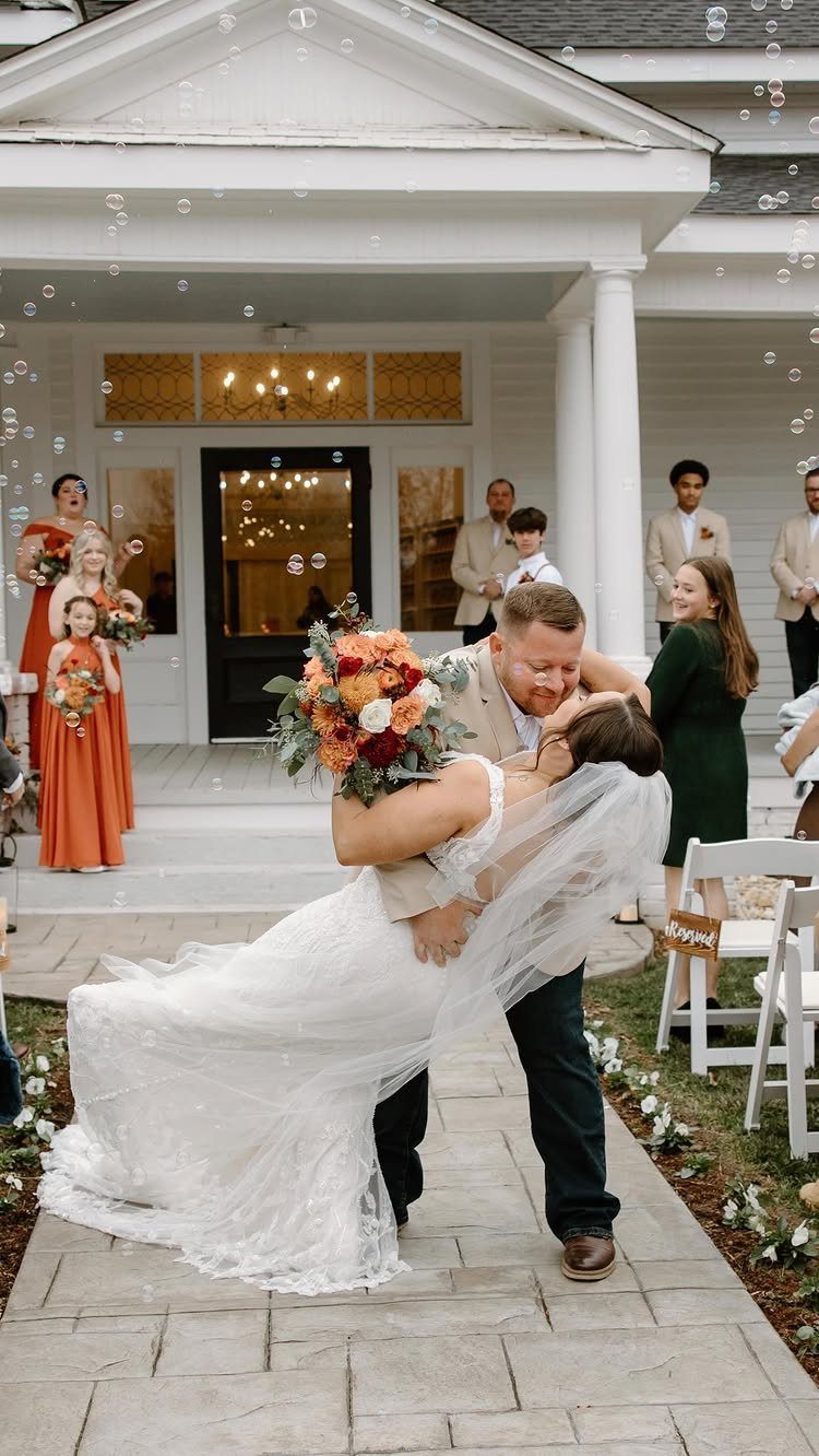 Groom dipping bride for a kiss on a stone aisle during wedding celebration