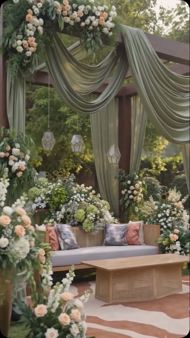 Outdoor lounge with sage green draping and peach and white floral arrangements.