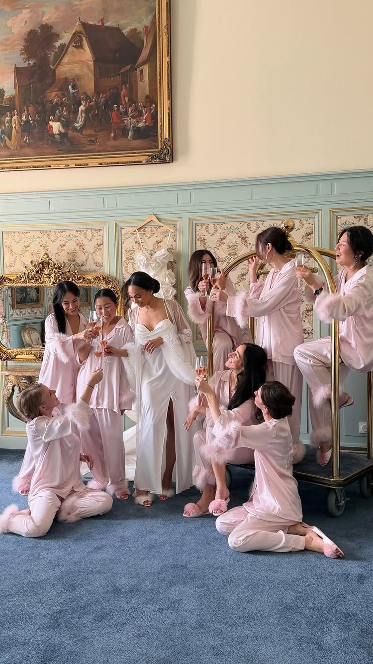 Bride and bridesmaids in robes celebrating with champagne in a decorated room.