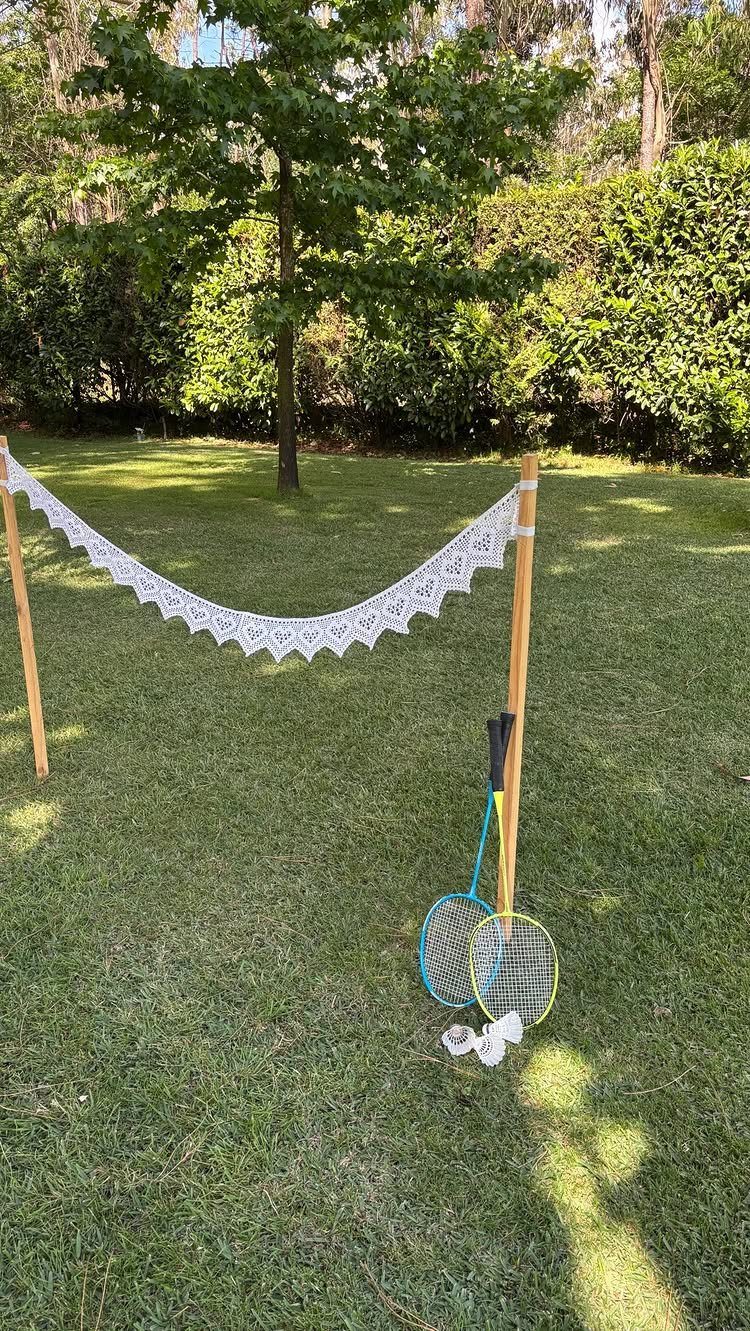 Badminton rackets and a lace net set up on a sunny green lawn.