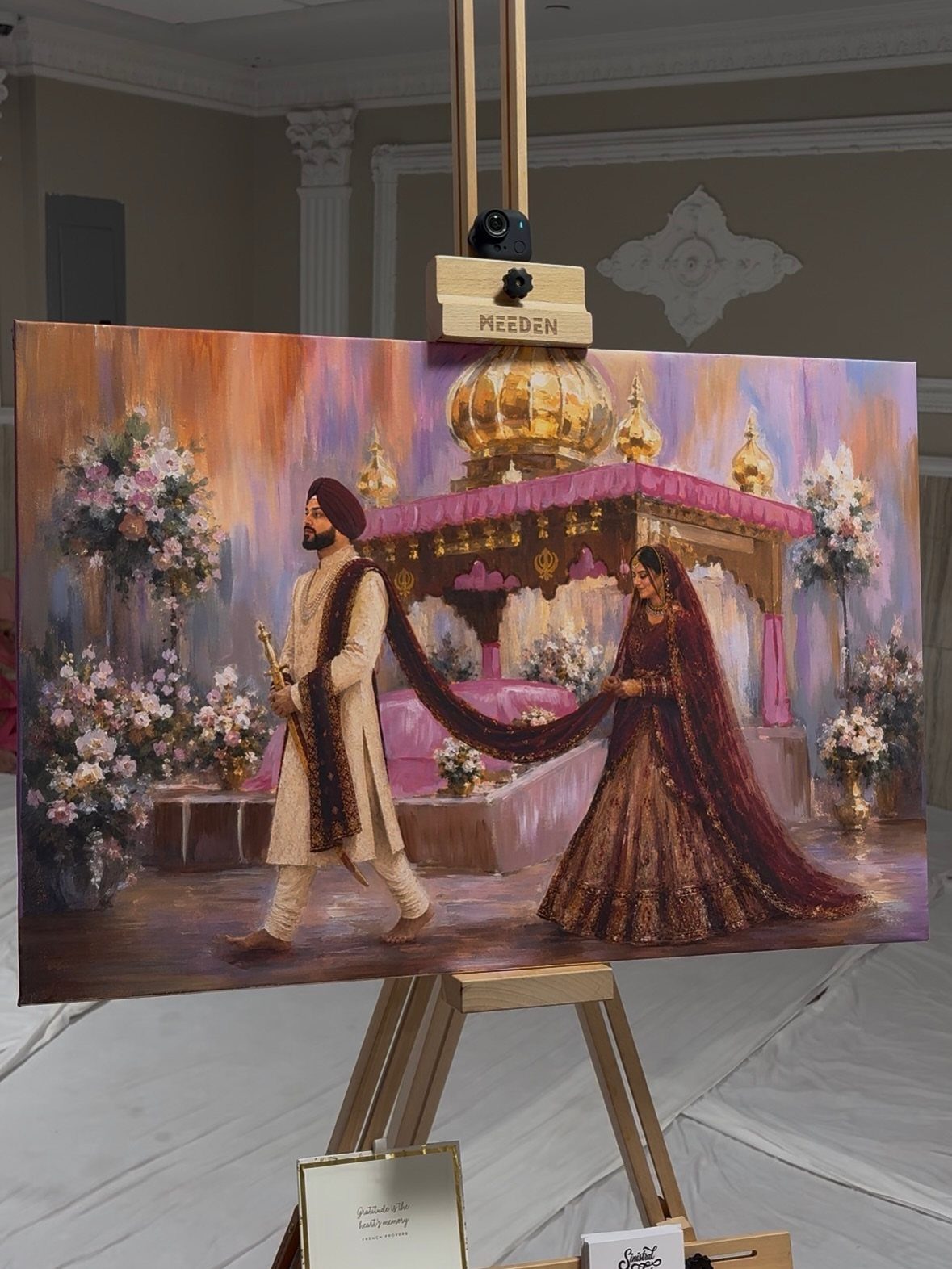 Painting of an Indian wedding couple on a canvas resting on a wooden easel